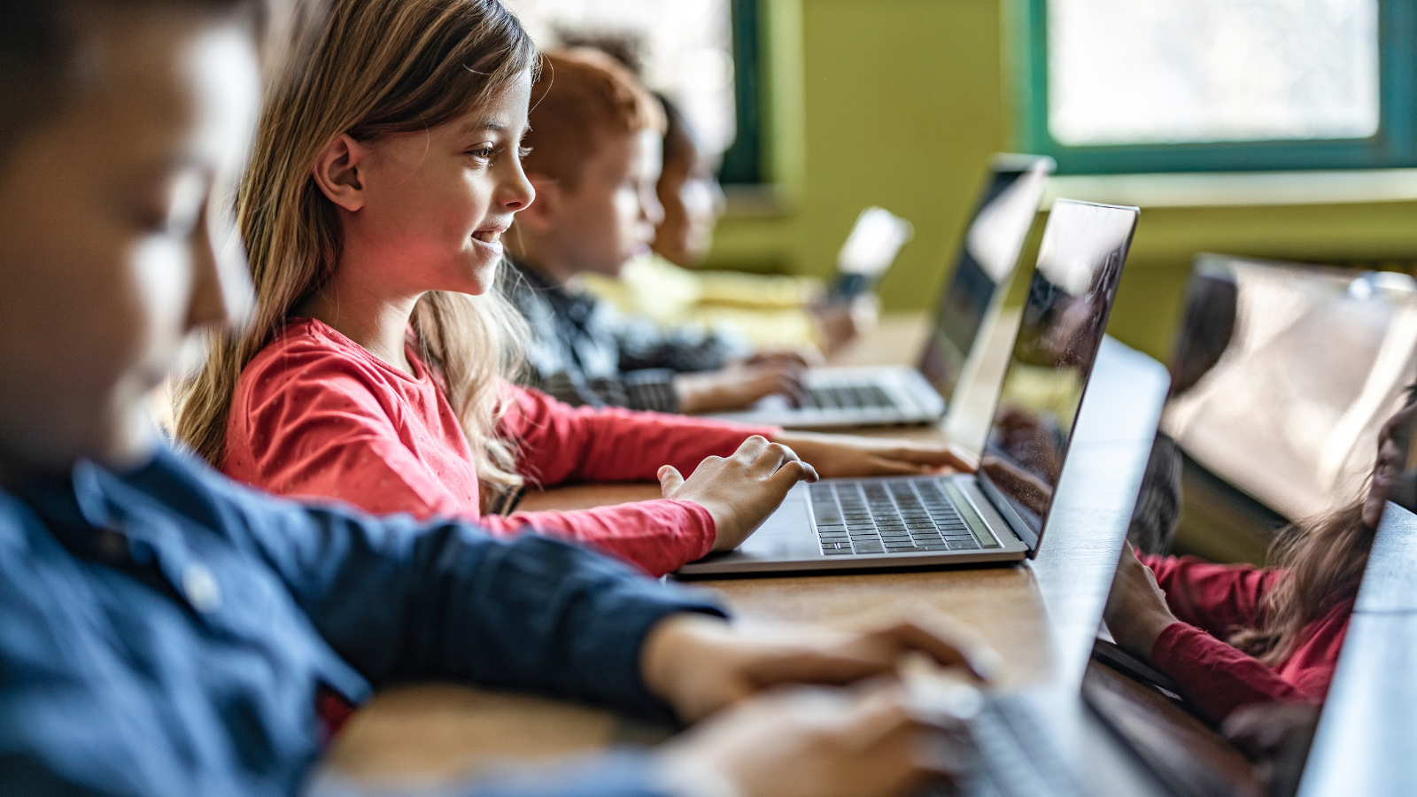 Elementary school students working on laptops at school